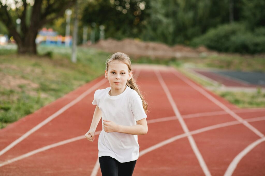 Focused child girl runner on a racing track. Confidence, empowerment and healthy physical habits.